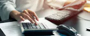 Person using a calculator and laptop