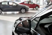 A black vehicle sits across from other cars at a dealership.