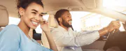 A smiling man and woman drive their car.