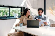 A couple checks their finances in their kitchen.