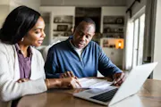A couple looks over their personal finances in their kitchen.
